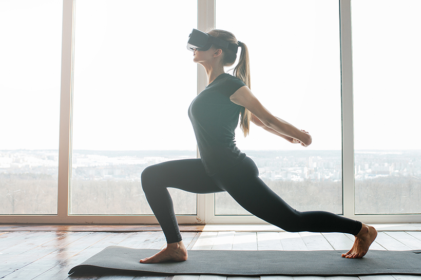 young woman doing yoga with a virtual reality headset