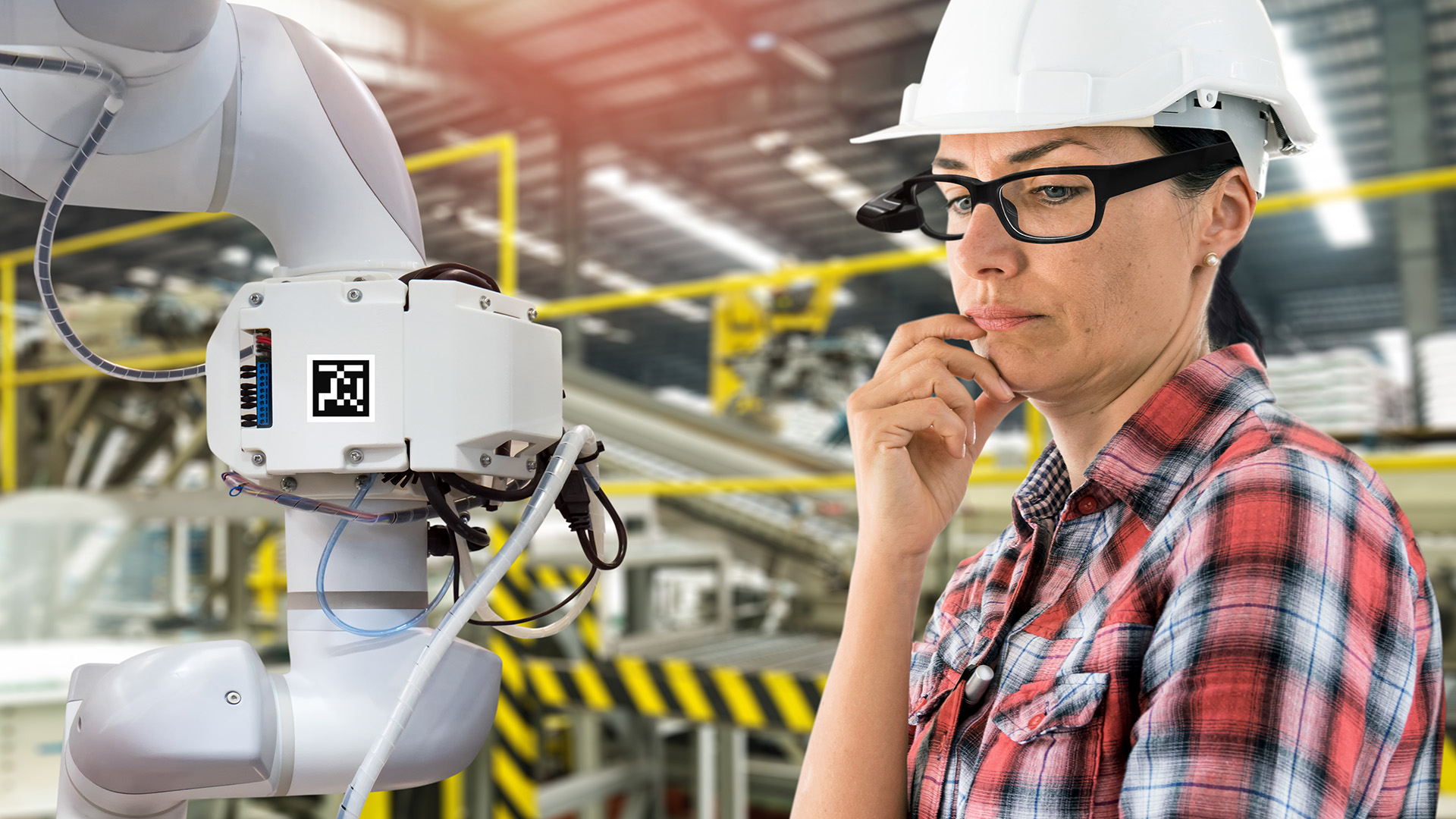 engineer woman wearing ar classes in a factory looking at robot arm